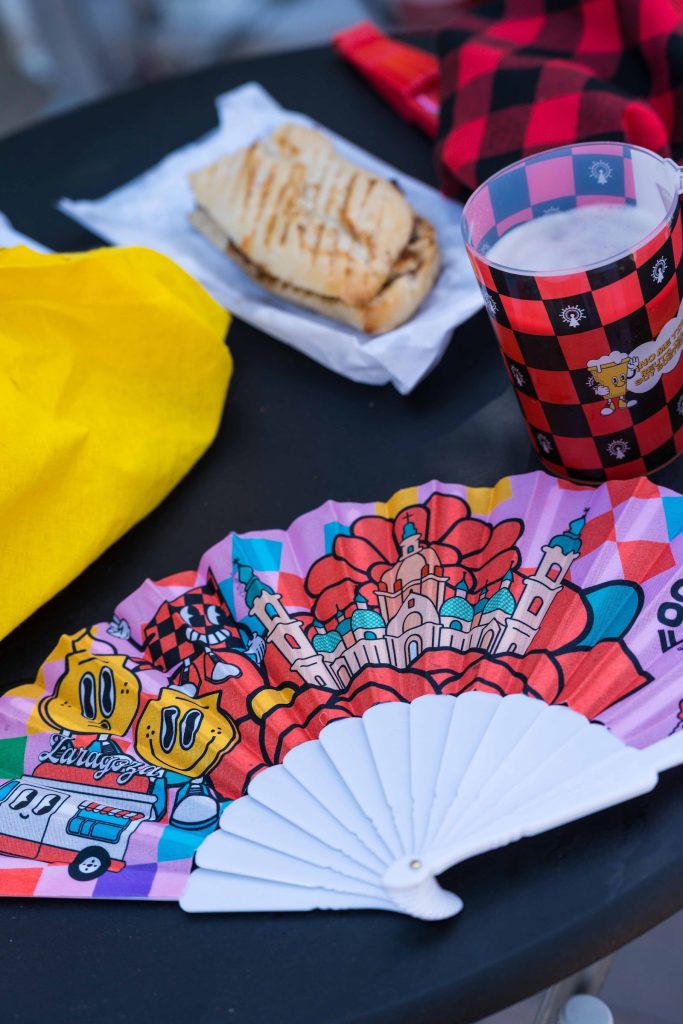 Bocadillo y vaso de Las Food Trucks con abanico de las Fiestas del Pilar de Zaragoza